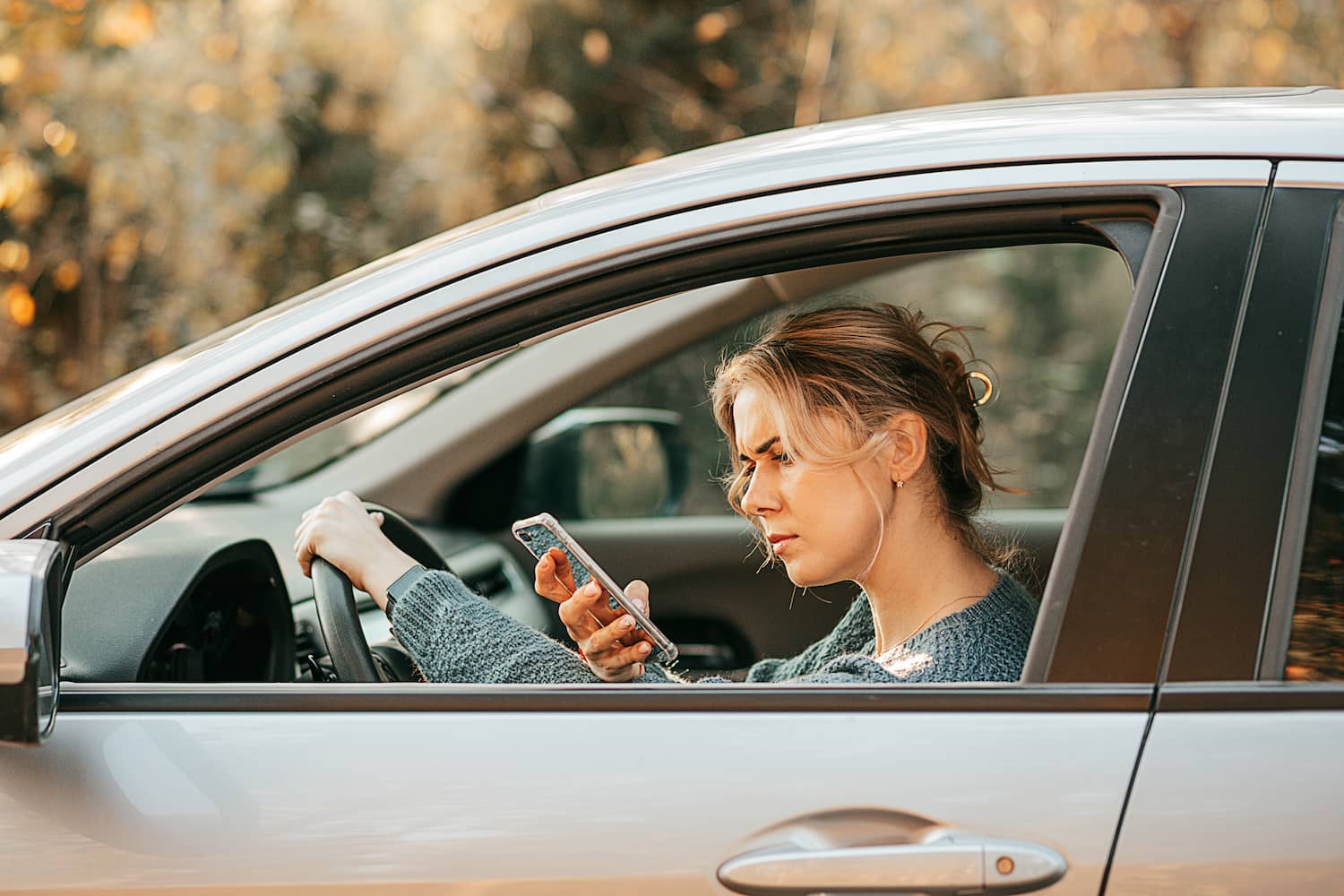 Photo of a woman looking at her mobile phone in a car