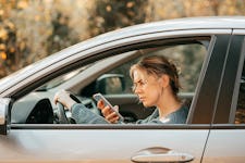 Photo of a woman looking at her mobile phone in a car