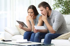 Worried couple looking at a tablet at home.