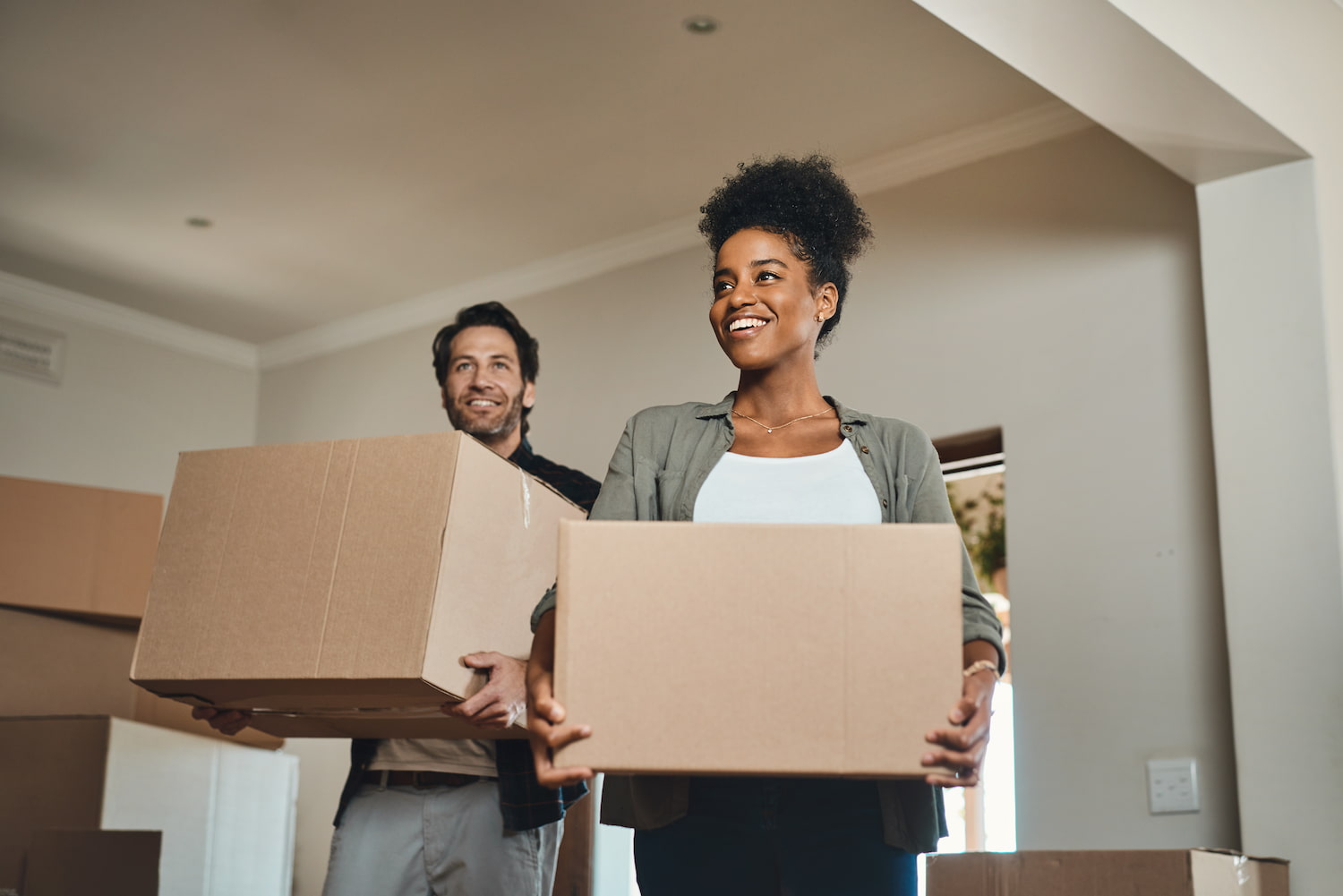 Shot of a couple smiling while carrying boxes into a condo home