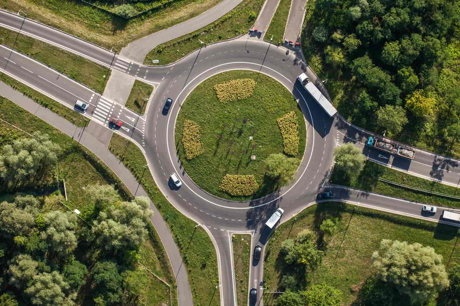 Aerial drone view of a vehicle and traffic in a roundabout.