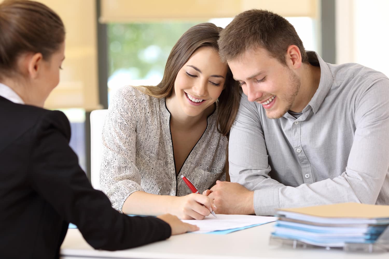 Happy couple signing a contract together at office.