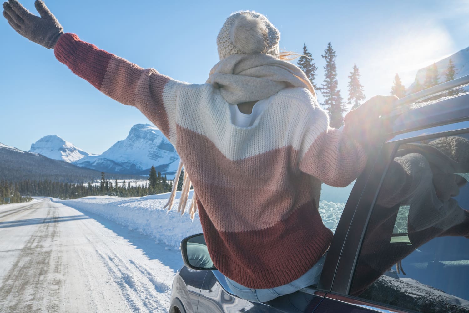 Person enjoying a scenic drive through a mountainous winter landscape.