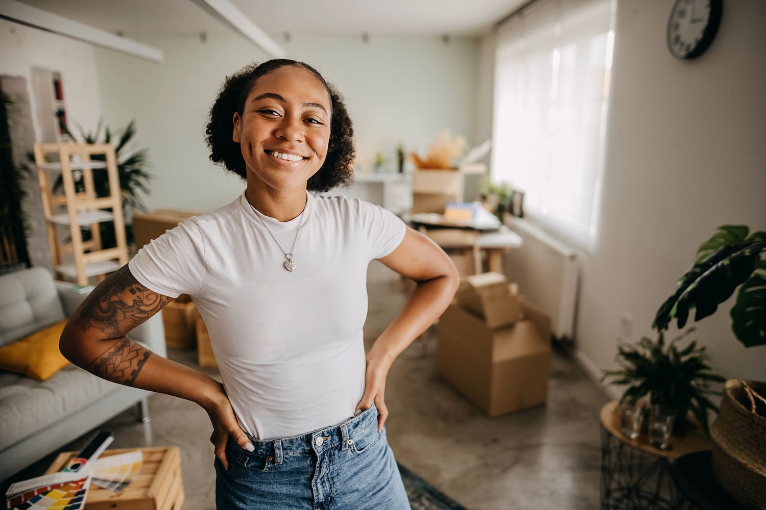 A person smiling while standing in the middle of an apartment.