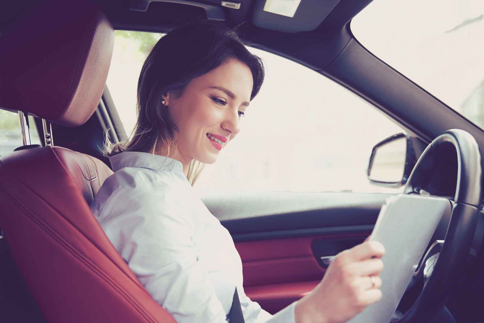 Woman smiling while sitting in the driver's seat of a car.