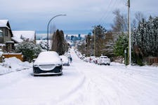 A street in Vancouver, British Columbia, Canada, it's not plowed and many parked cars covered with snow.