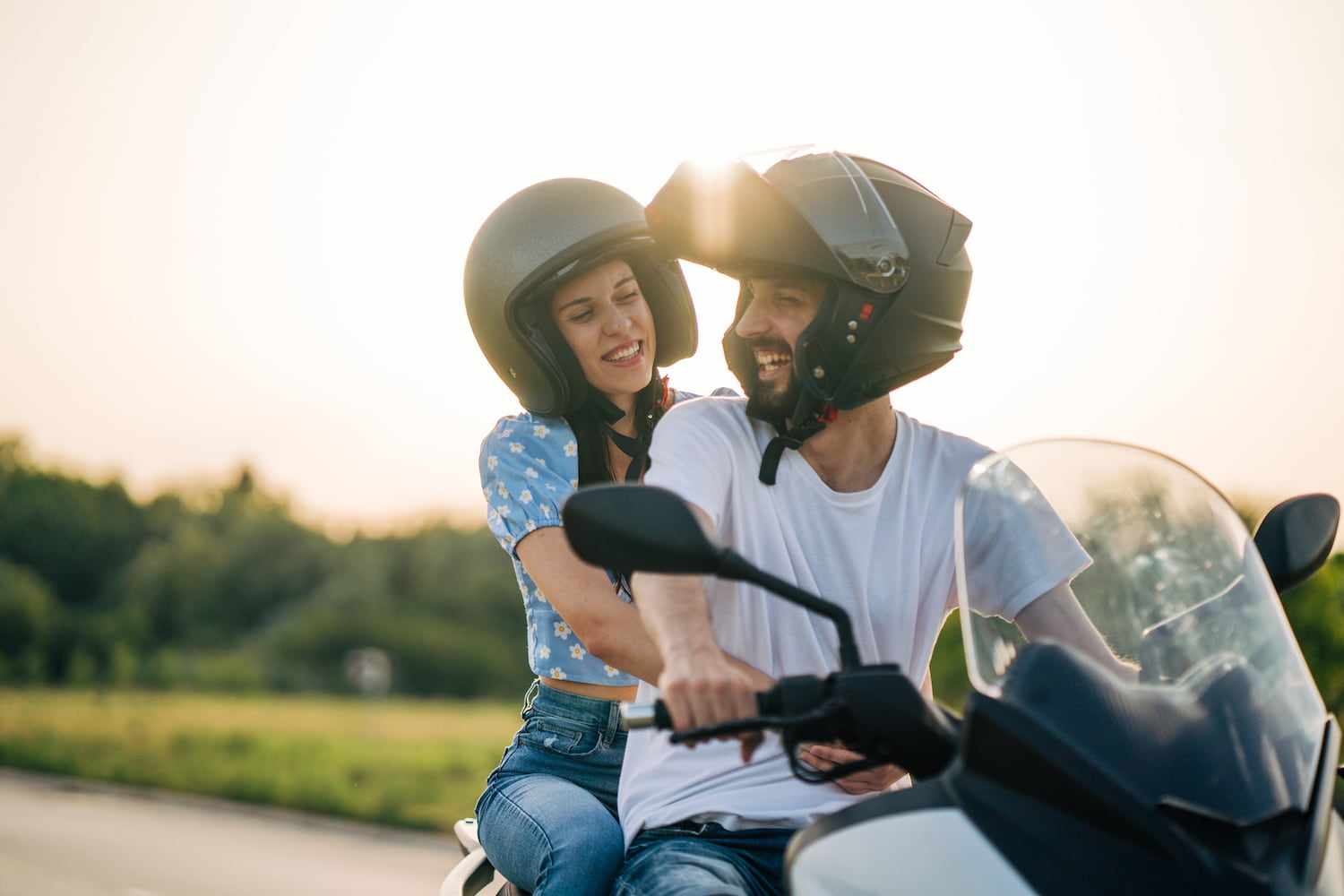 Happy young couple riding on a motorcycle on the road in nature.