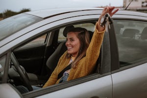 A young woman with a happy expression on her face, holding her new car keys