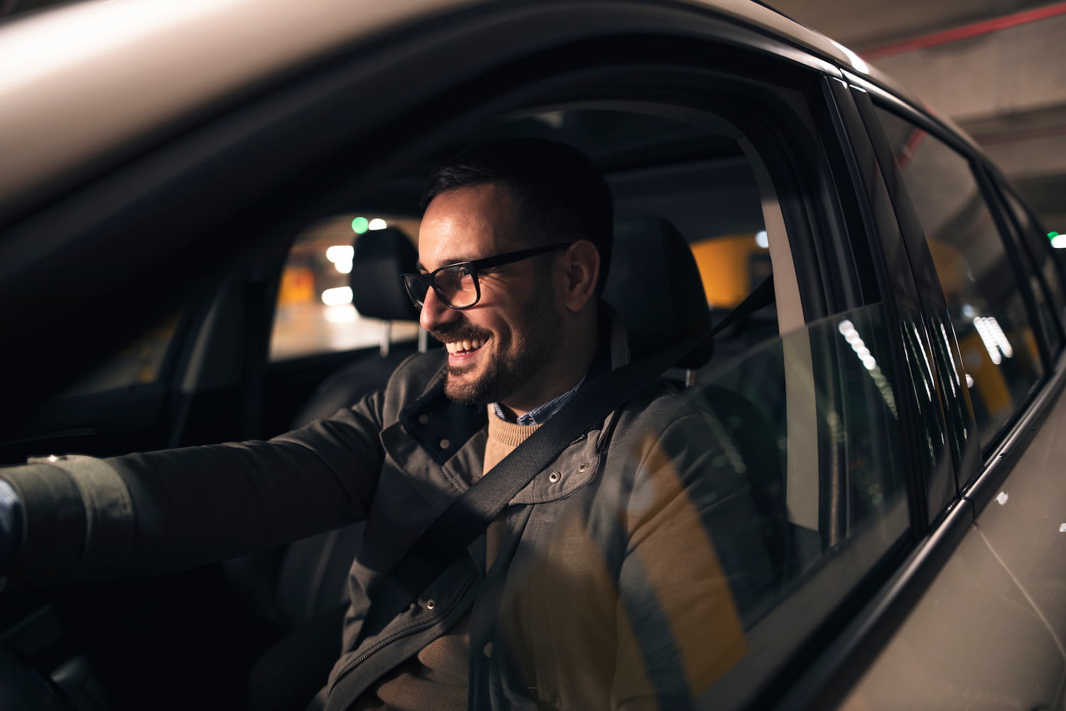 A person is wearing glasses, driving new car at night.