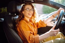 Stylish woman wearing an orange shirt and driving a car.