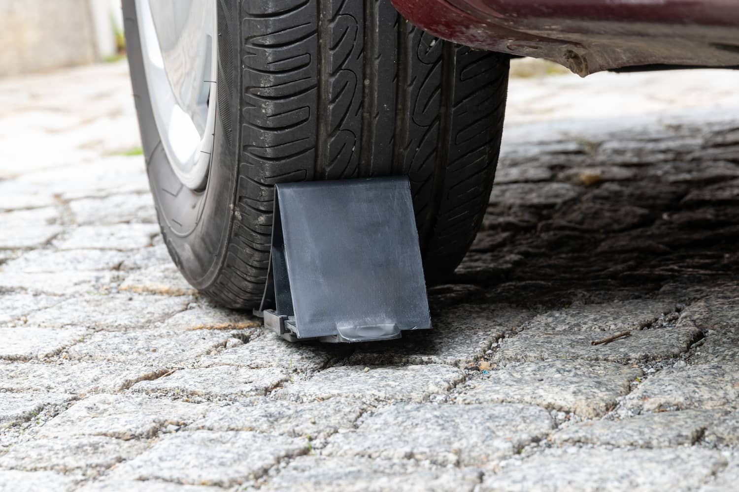 Vehicle wheel securely chocked on cobblestone street.
