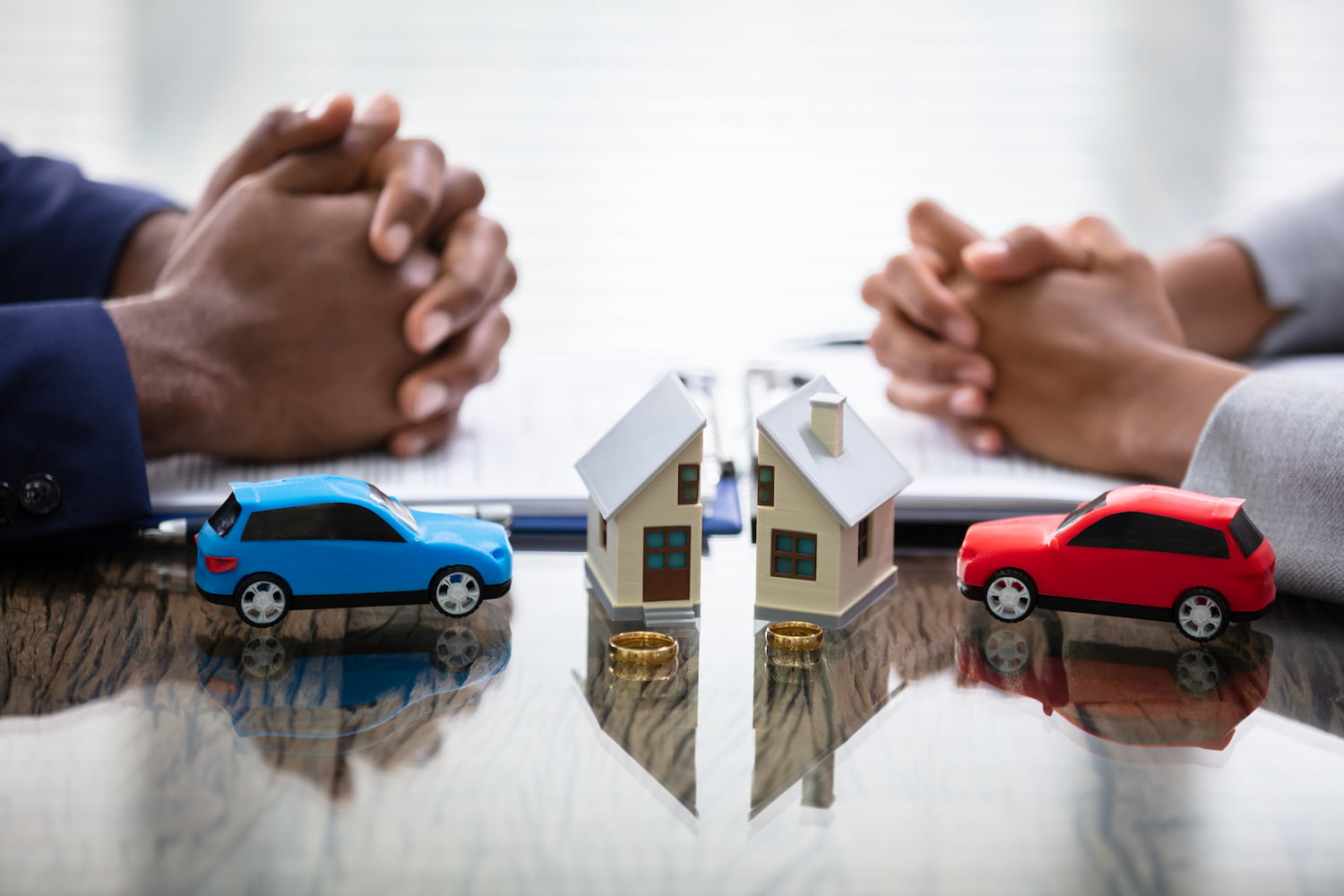 Two people at a table with small house and car models.