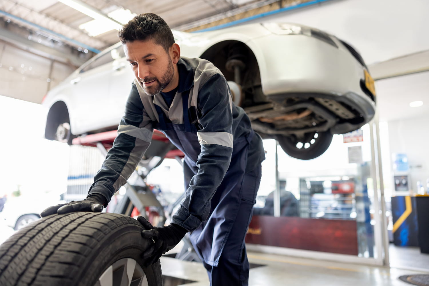 Happy mechanic changing a flat tire on a car.