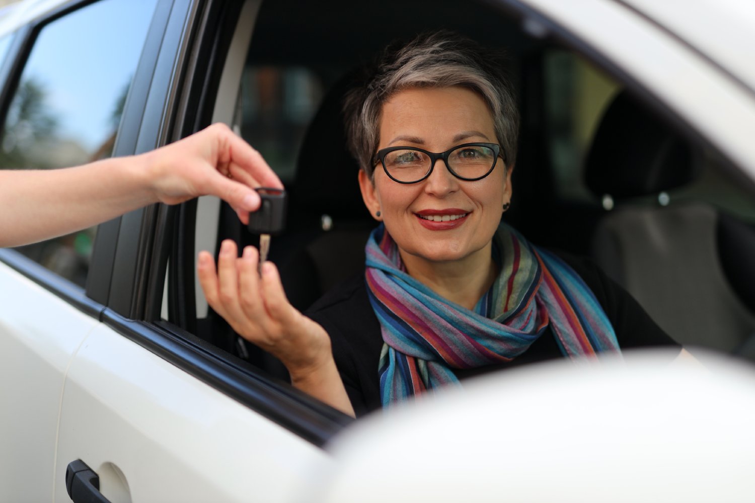 Someone hands a smiling woman car keys.