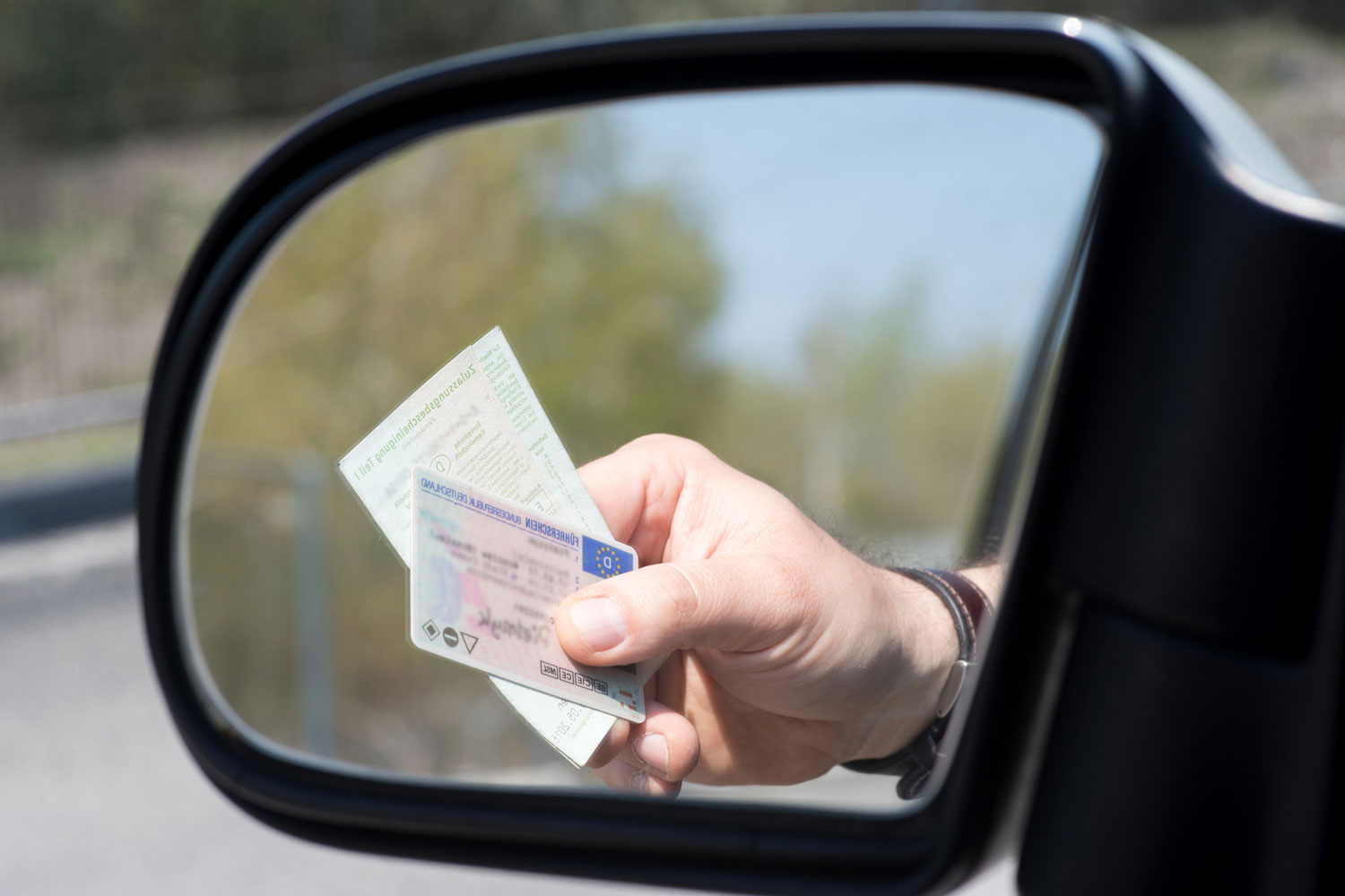 A man shows driver's license and vehicle registration at a check.