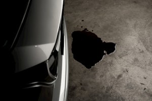 A closeup of an oil spill next to a car