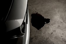 A closeup of an oil spill next to a car