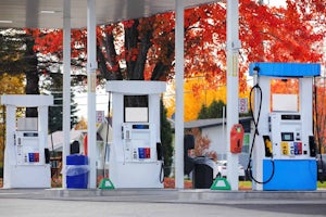 Three Modern Gas Pumps with Colorful Trees in Background