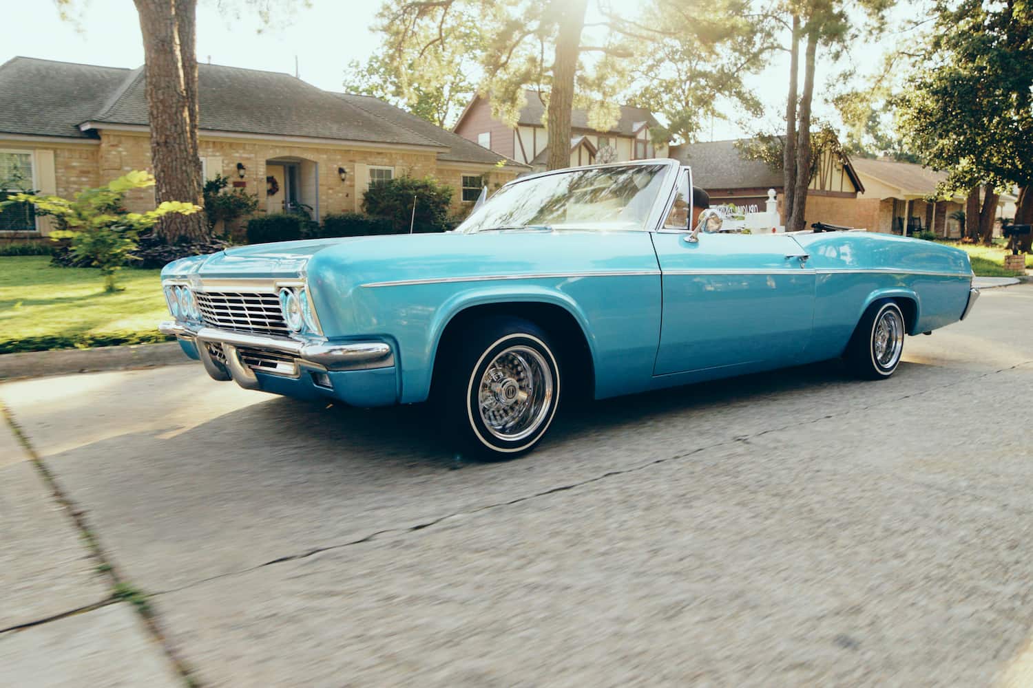 Blue vintage car driving down a street