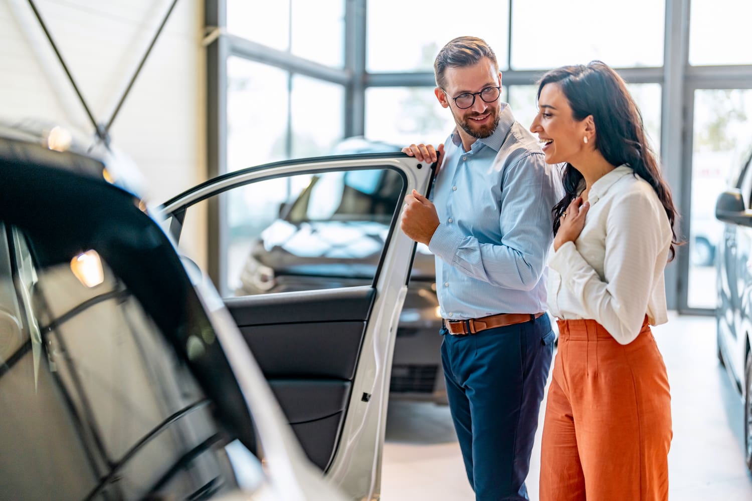 Woman checking a car from a seller in an auto dealership