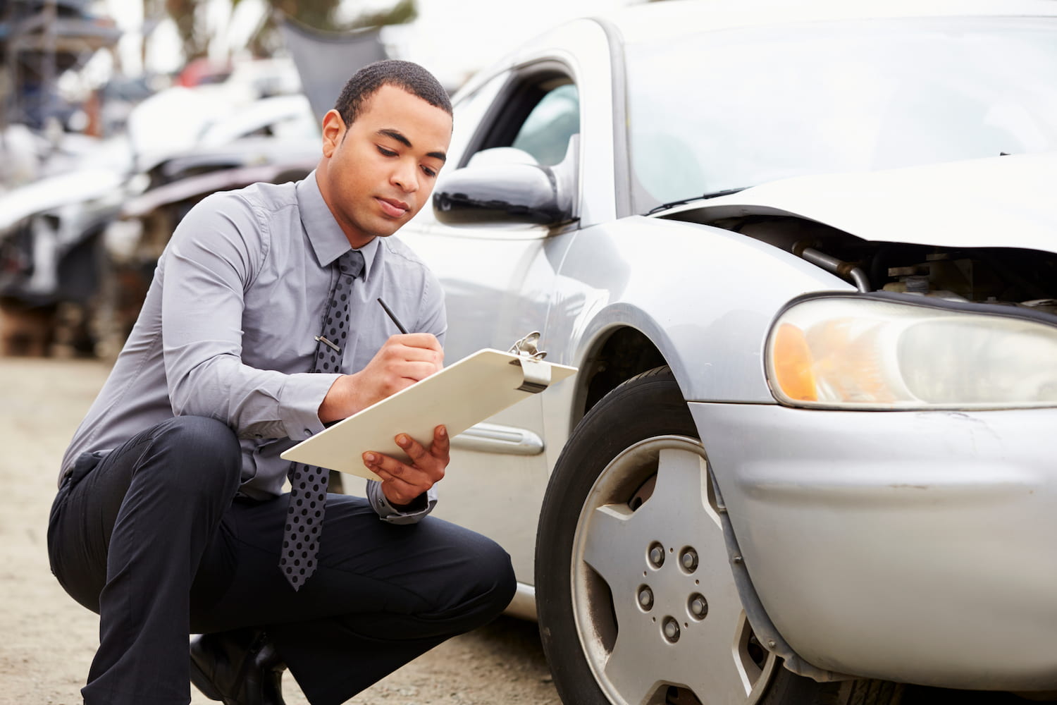 An individual Inspecting Car Involved In Accident Crouching Down