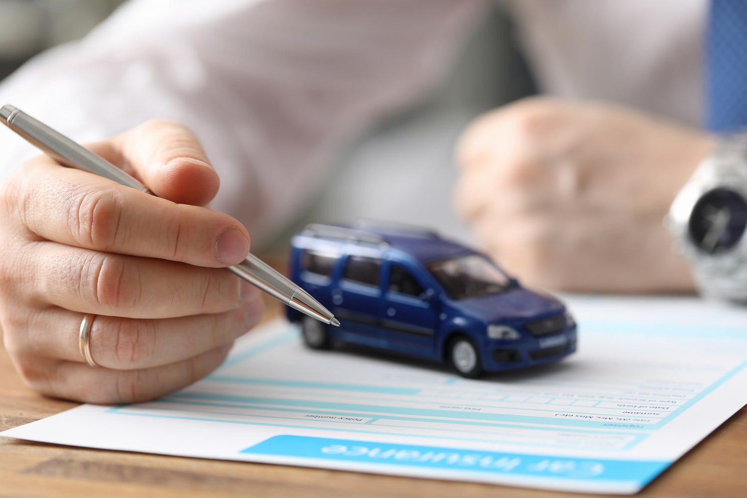 Close-up of man hand reading car insurance and getting ready to sign.