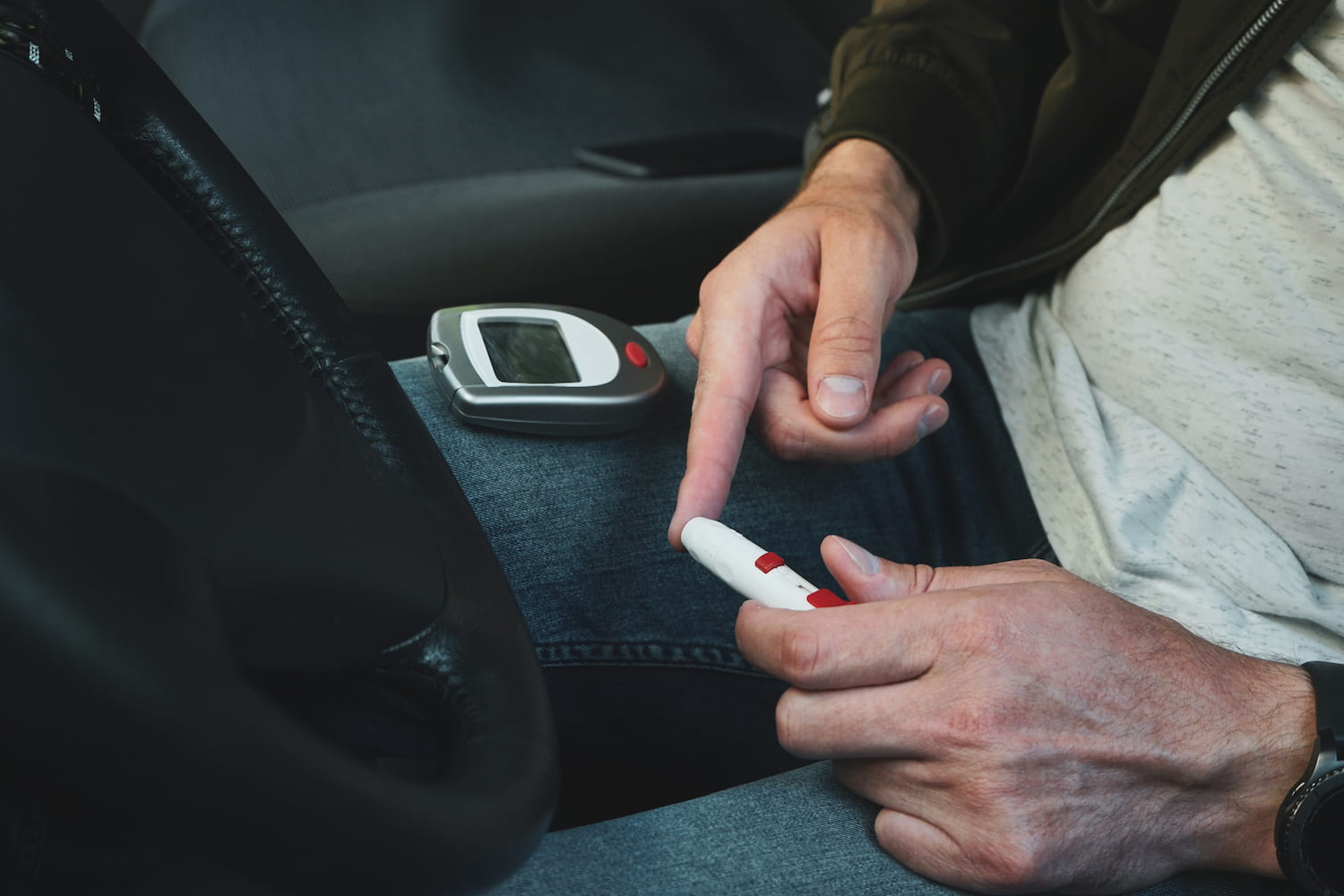 Diabetes Lancet pen and glucometer in the hands of a person in a car.