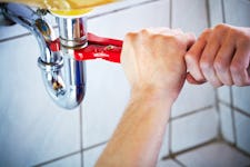 Plumber hands holding wrench and fixing a sink