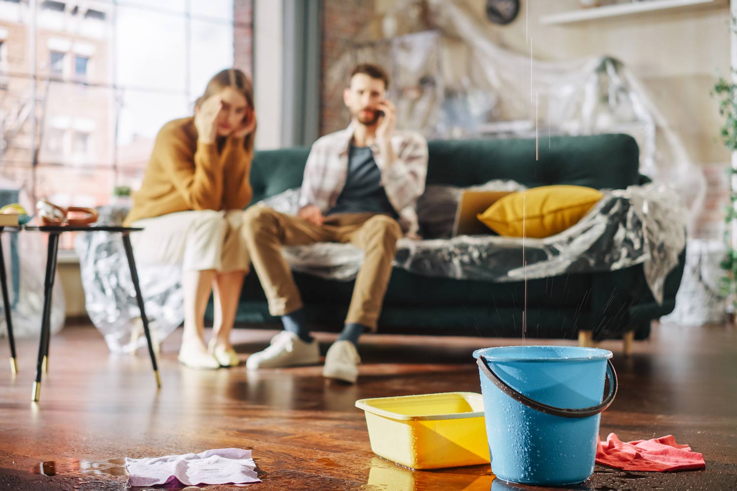 Anxious Couple Watching Water Drip into Buckets in Their Living Room.