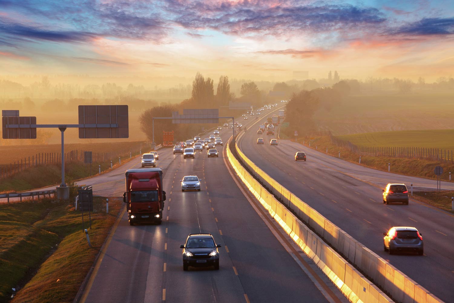Highway with cars and a truck. Beautiful sky in background.