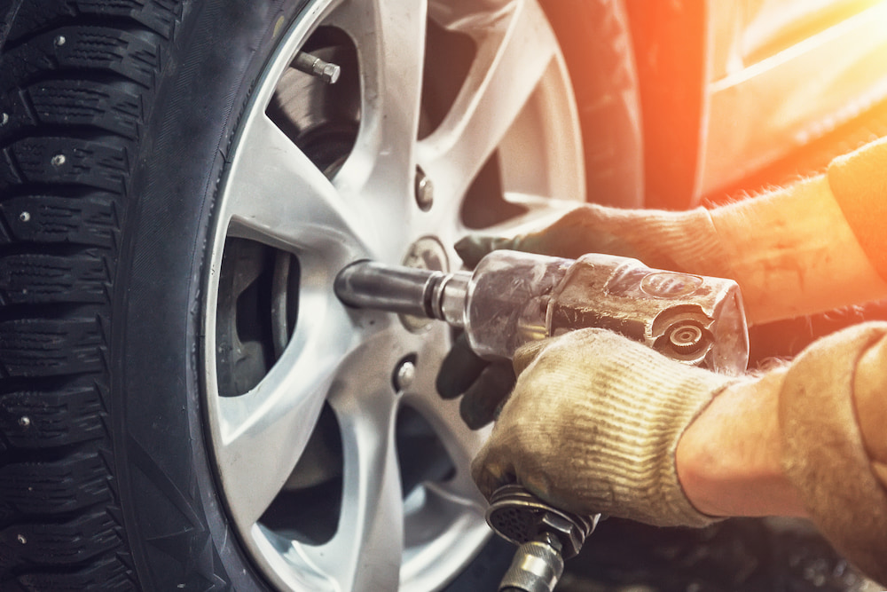 A mechanic works on the wheels while wearing protective gloves.