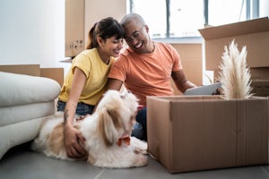 A happy couple and their dog opening a box in their new home
