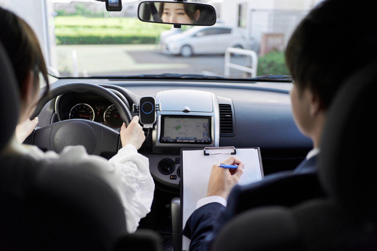 Person taking road test with examiner in passenger seat.