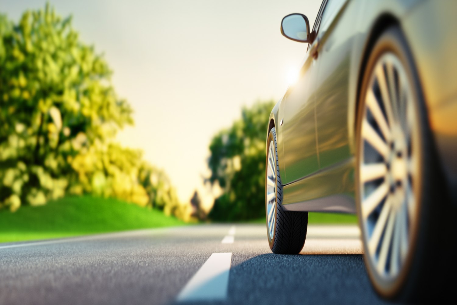 Close-up of back tires on a car driving down road.
