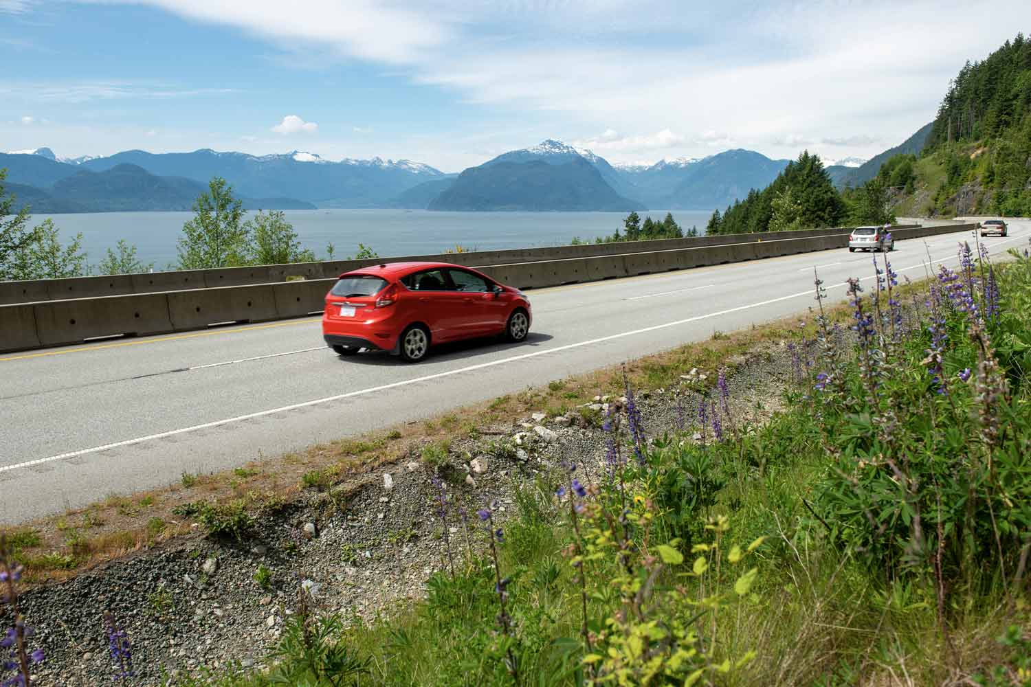 Vehicles on mountain highway near pacific ocean.