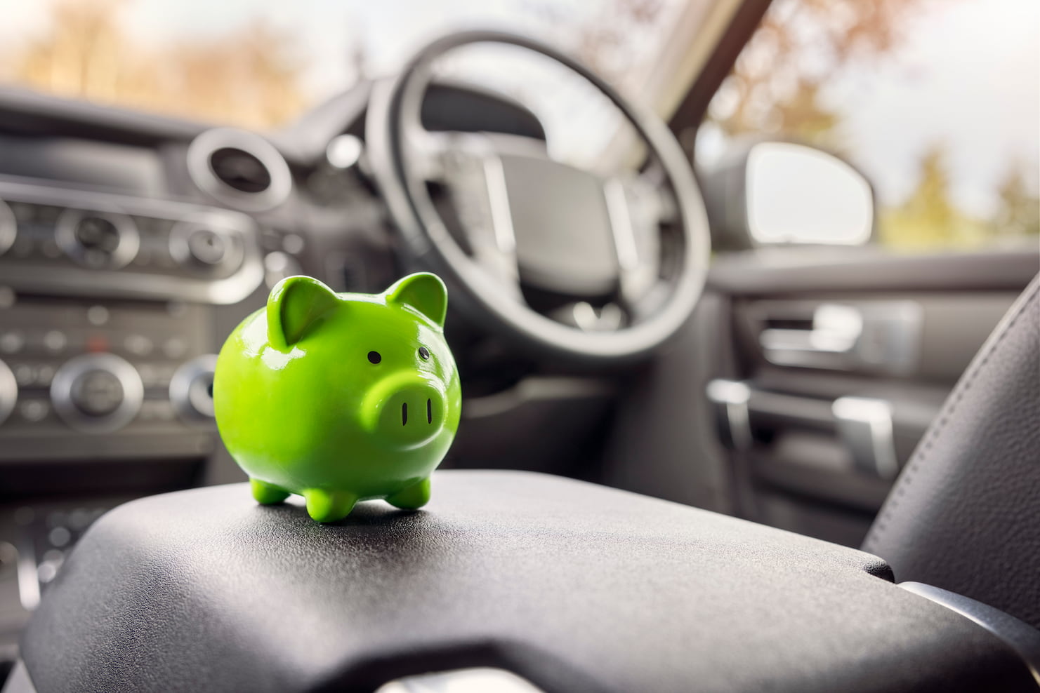 Green piggy bank inside a car.