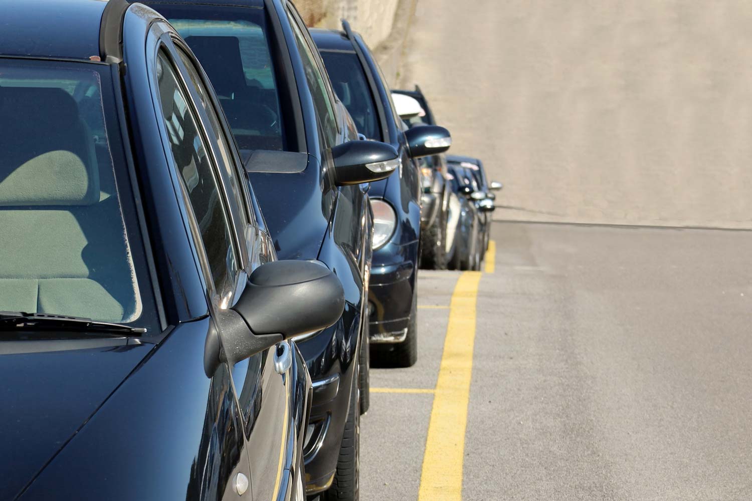A row of cars parked on an incline, focusing on their rear-view mirrors.