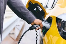 Man's hand plugging electric charger into yellow electric car