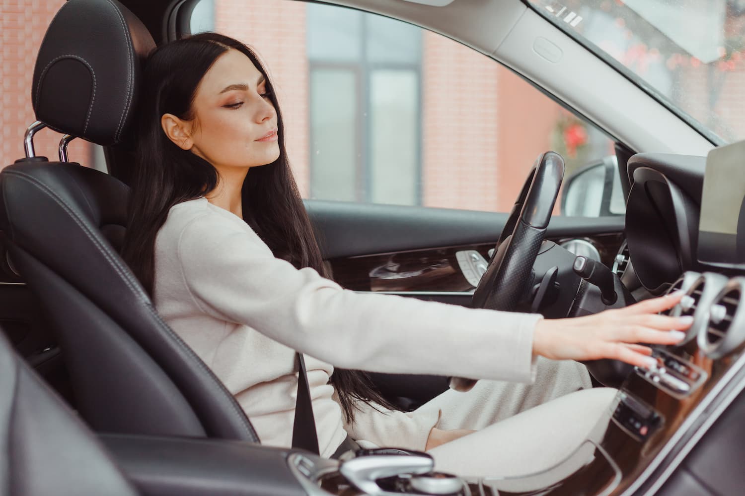 Woman turning on car air condition system on dashboard in car panel.