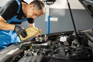 A mechanic pouring oil into a car engine