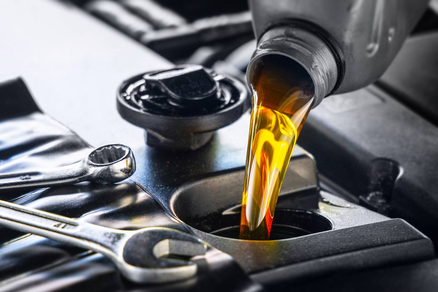 Pouring motor oil for motor vehicles from a gray bottle into the engine.