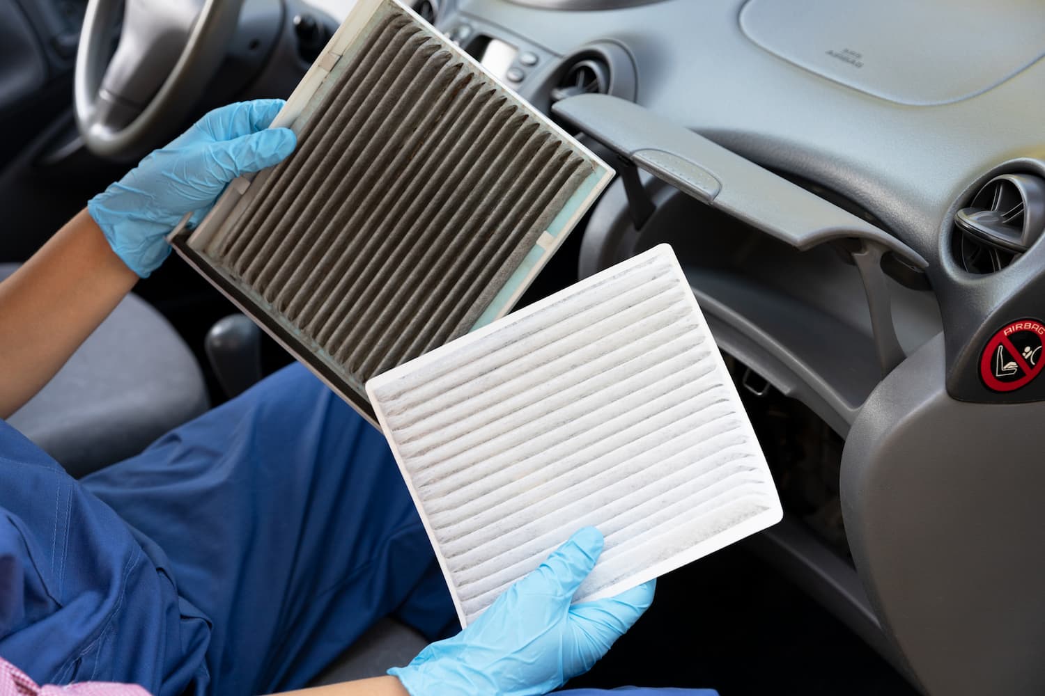A person setting in a car and holding clean and dirty cabin air filters