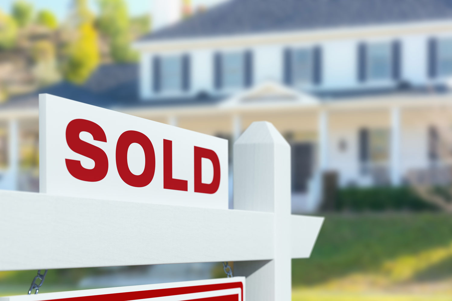 Sold sign in front of a house with a "For Sale" sign.