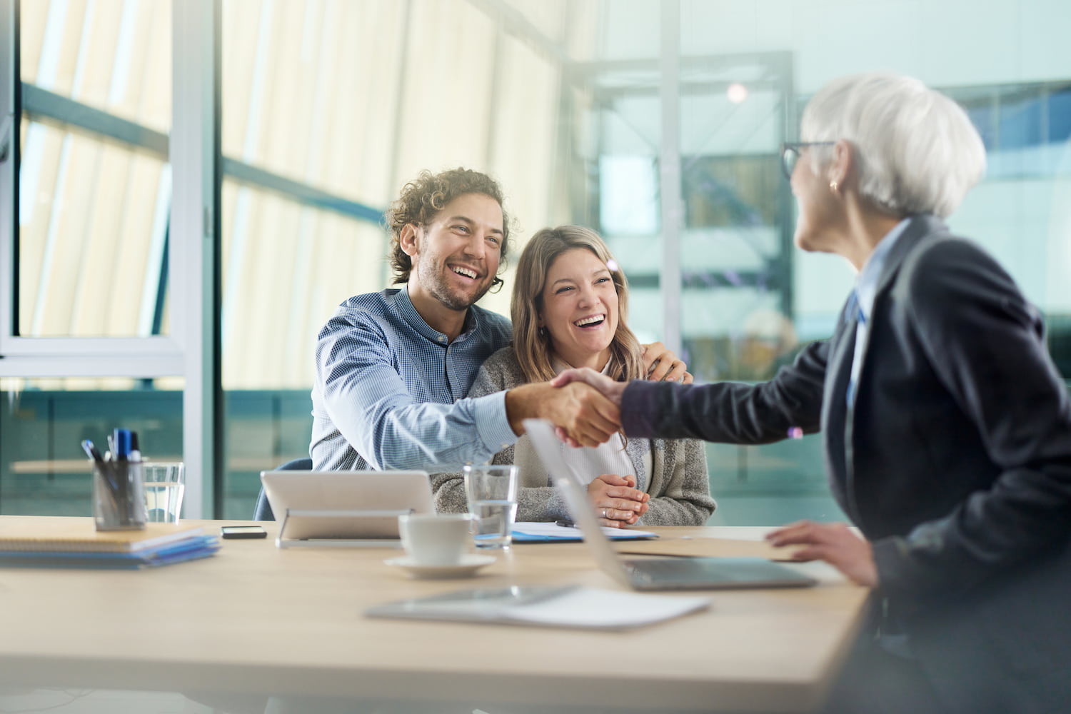 A happy couple reaching an agreement with a professional during a meeting in an office.