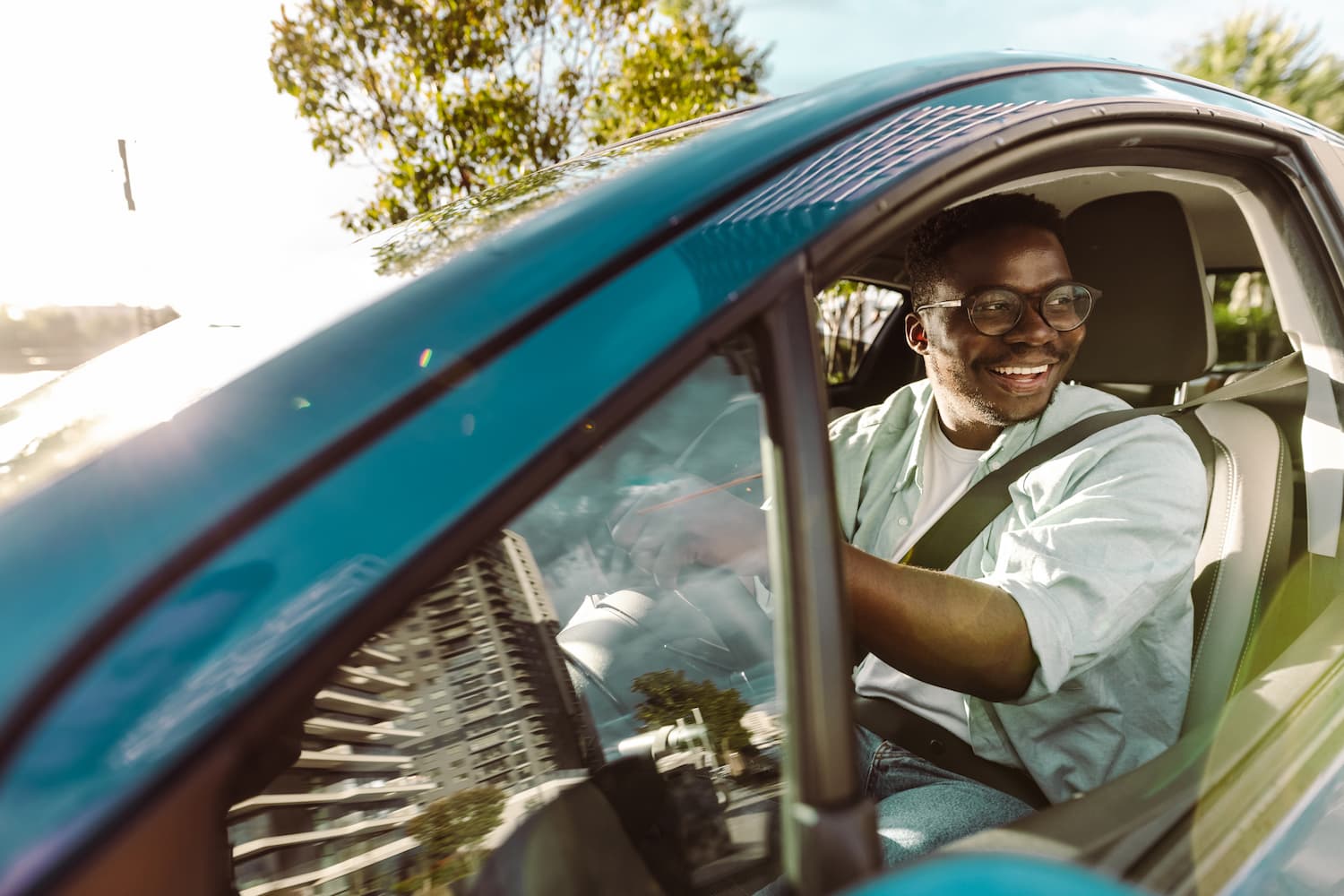 Smiling man holding the steering wheel and smiling while driving a car.