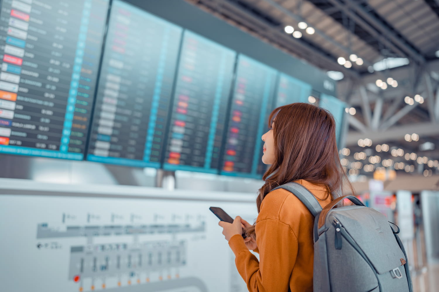 A happy person checks the departure schedule in an airport terminal.