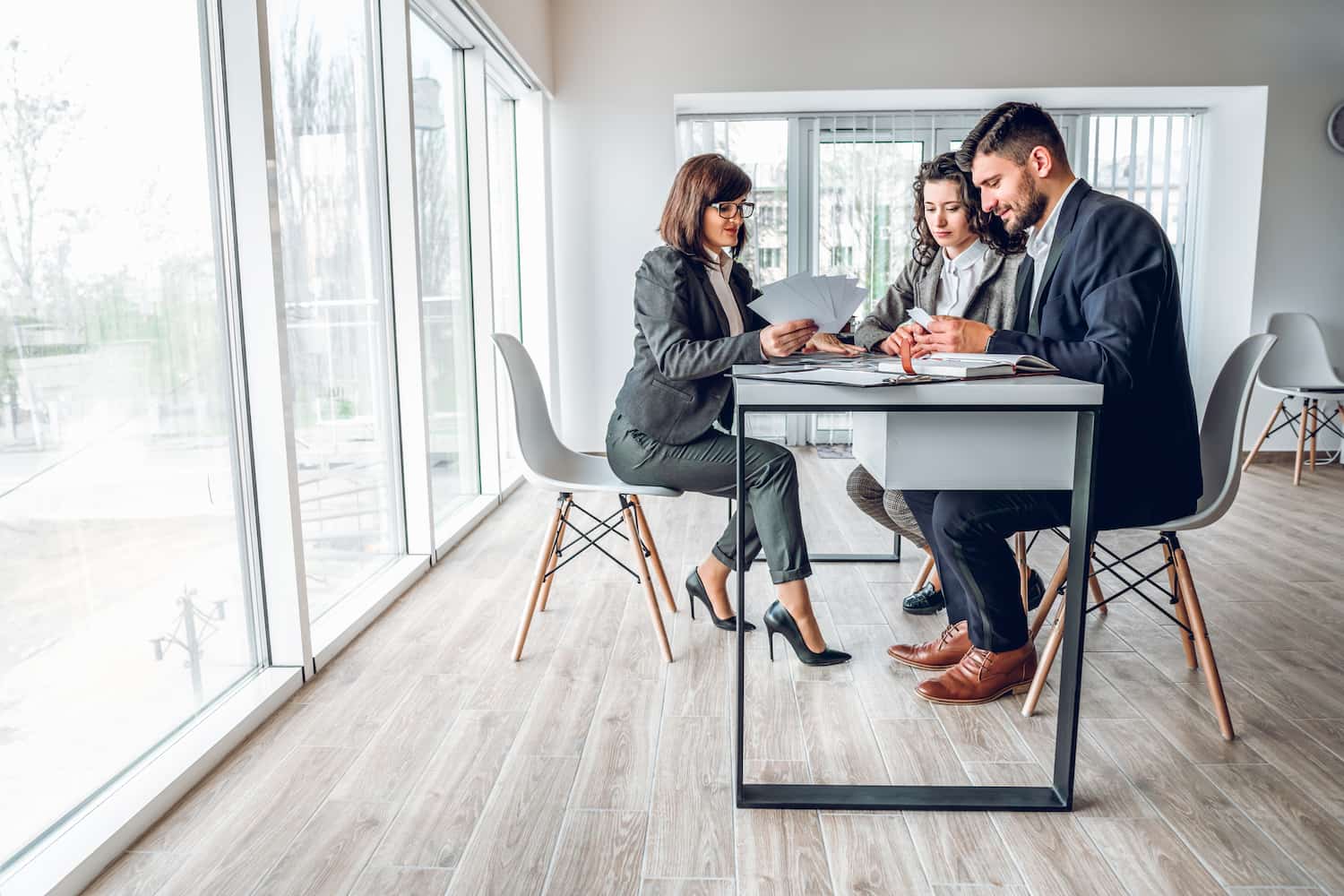 Wide angle view of group business people in bright spacious modern office near panoramic windows.