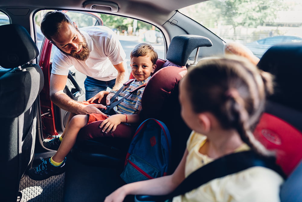 A father adjusting his kids safety seat belts