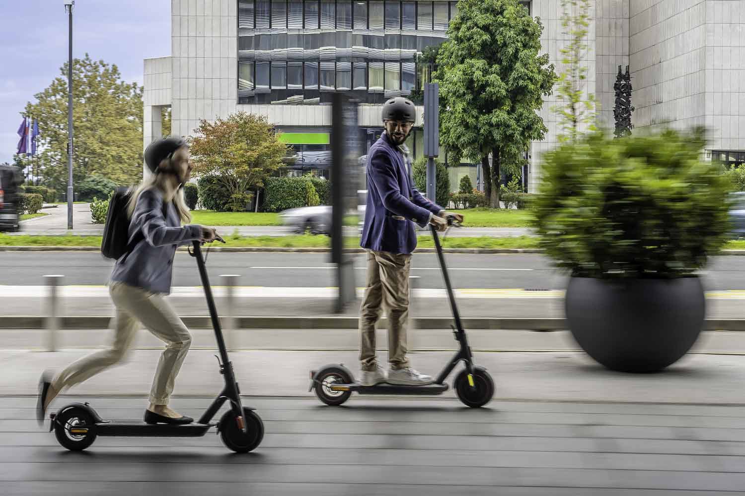 Smiling people riding electric scooter.