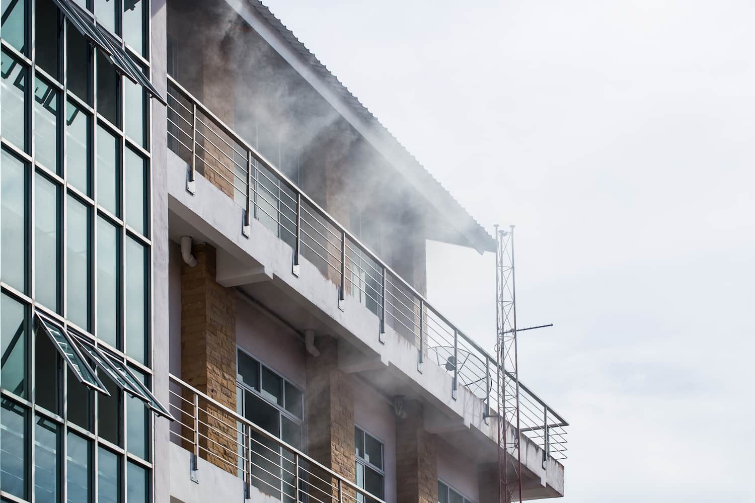 Smoke rising from the front of a tall building due to a fire.